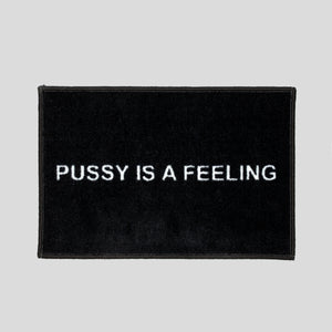 Black doormat with white PUSSY IS A FEELING sign designed by Identities Brand.