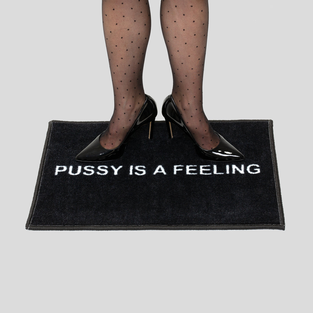 Black doormat with white PUSSY IS A FEELING sign designed by Identities Brand.
