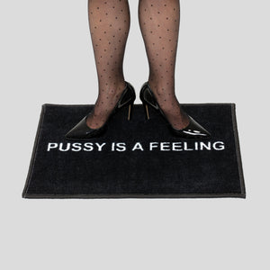 
            
                Load image into Gallery viewer, Black doormat with white PUSSY IS A FEELING sign designed by Identities Brand.
            
        